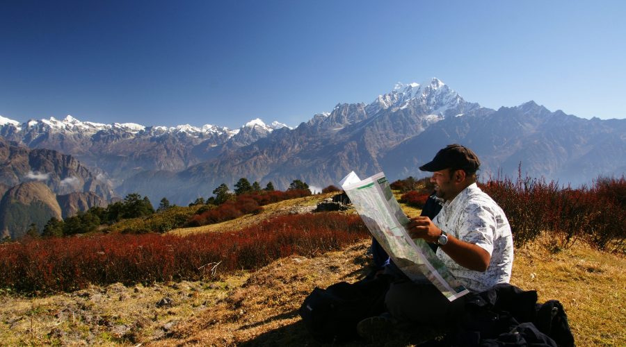  trekking guide looking at a map in nepal in front of a mountain range in tamang heritage trail 